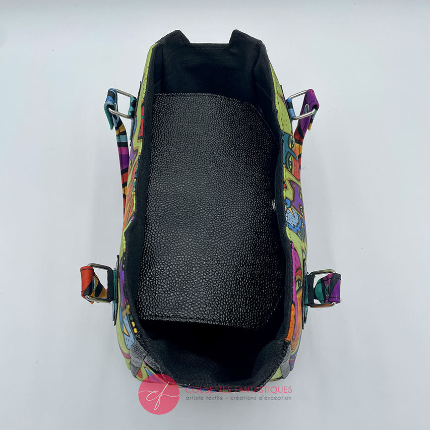 A small handbag made of shiny black faux galuchat texture and a silk scarf with a very colorful cat motif.