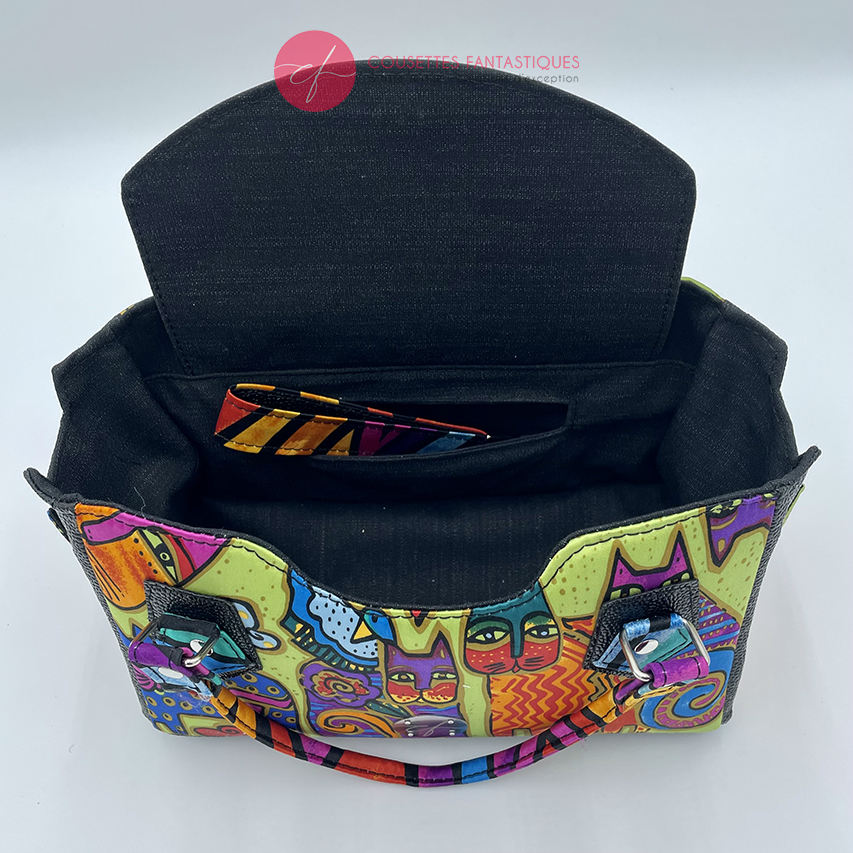 A small handbag made of shiny black faux galuchat texture and a silk scarf with a very colorful cat motif.