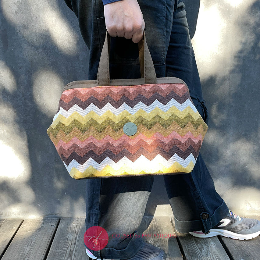 A handbag made of wrap fabric with a giant chevron pattern in autumn tones (pink, brown, orange, yellow, and white).