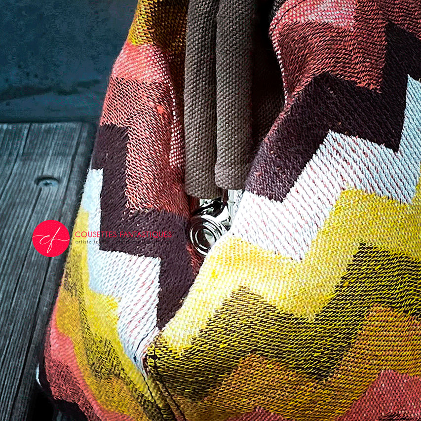 A handbag made of wrap fabric with a giant chevron pattern in autumn tones (pink, brown, orange, yellow, and white).