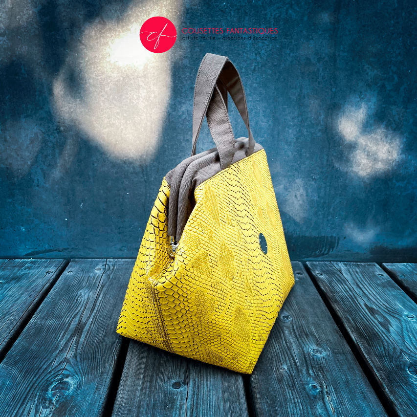 A handbag made with crocodile-textured yellow and brown synthetic leather.