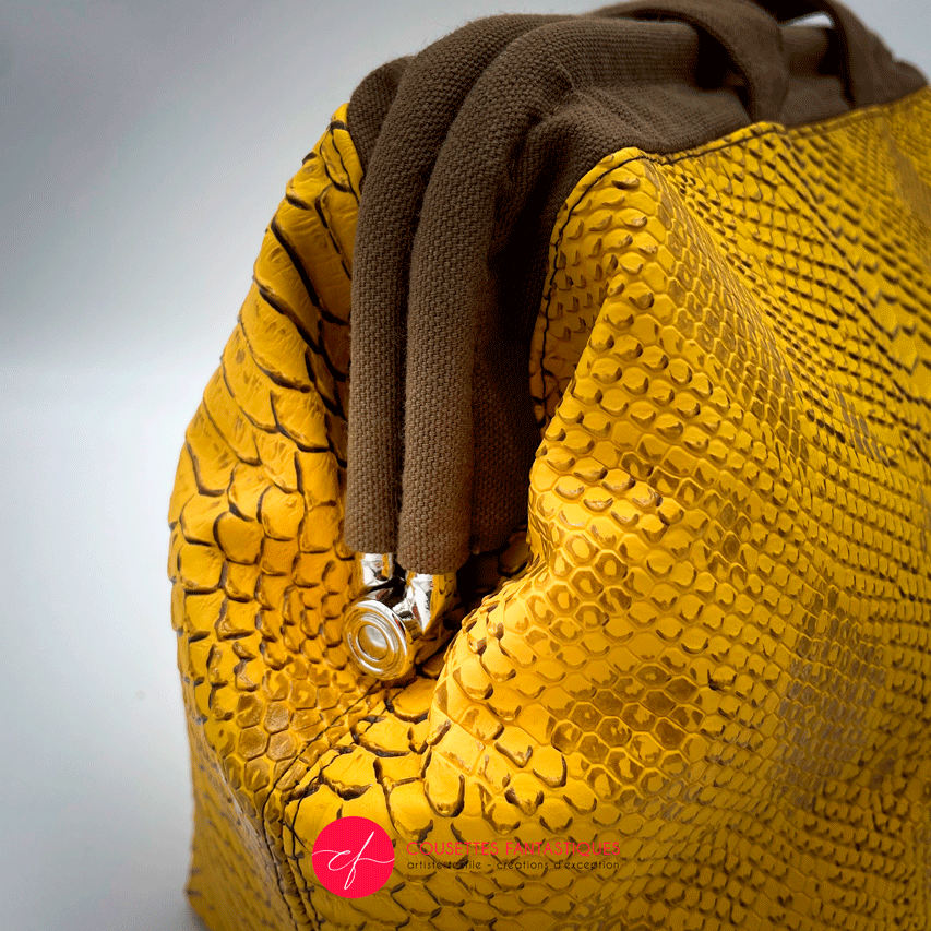 A handbag made with crocodile-textured yellow and brown synthetic leather.