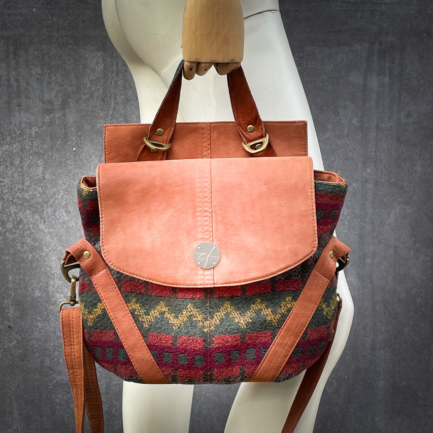 A medium-sized bag, worn over the shoulder, by hand, as a crossbody, or on the back, in chestnut suede and geometric patterned wool fabric, with a viscose lining featuring a geometric motif.