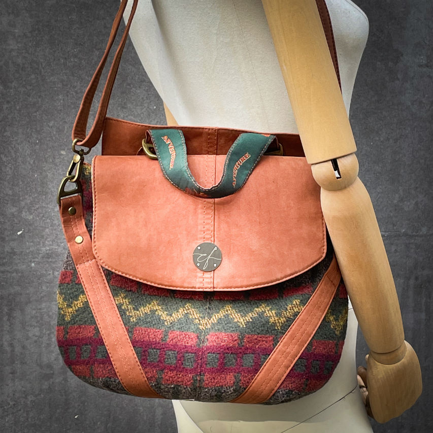 A medium-sized bag, worn over the shoulder, by hand, as a crossbody, or on the back, in chestnut suede and geometric patterned wool fabric, with a viscose lining featuring a geometric motif.