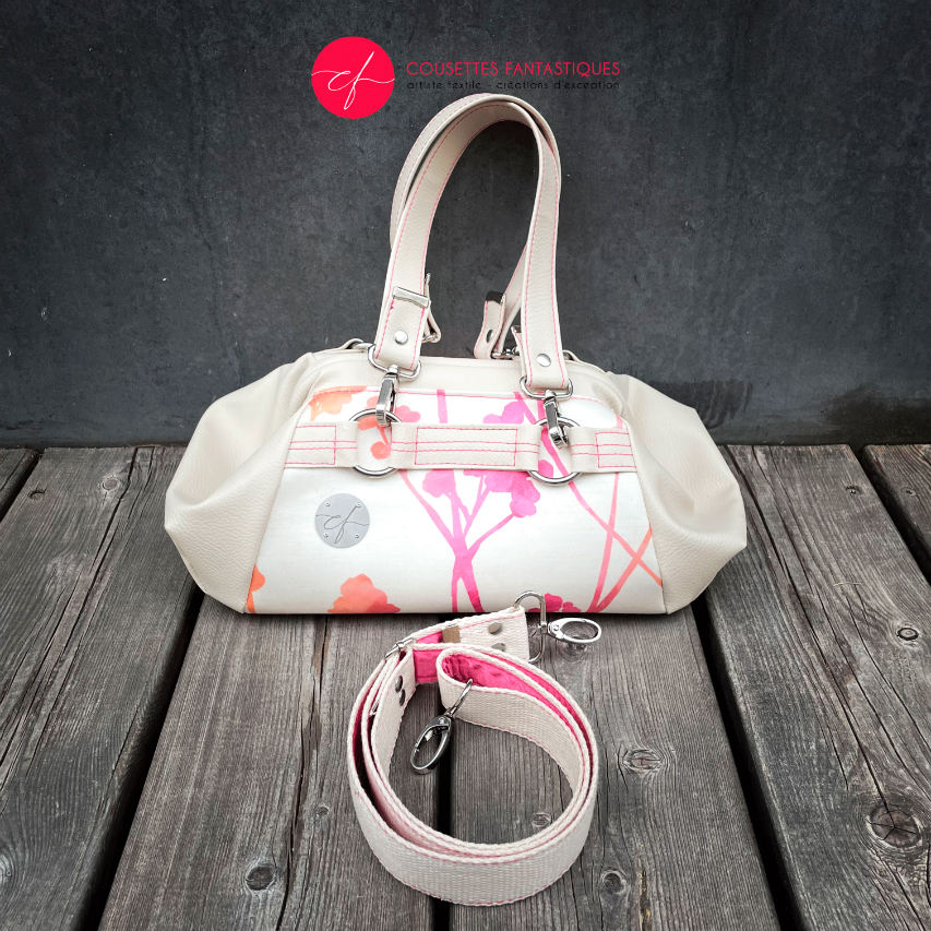 A small handbag made of cream synthetic upholstery fabric with a botanical pattern that fades from pink to orange.