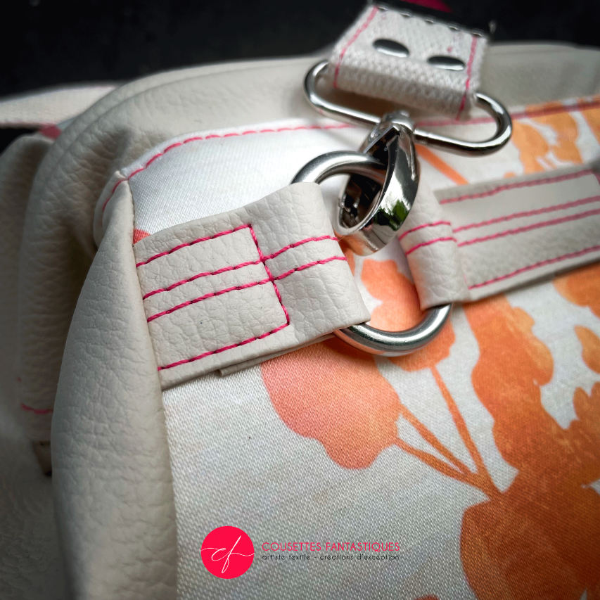 A small handbag made of cream synthetic upholstery fabric with a botanical pattern that fades from pink to orange.