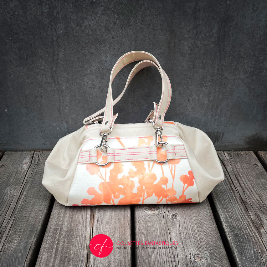 A small handbag made of cream synthetic upholstery fabric with a botanical pattern that fades from pink to orange.