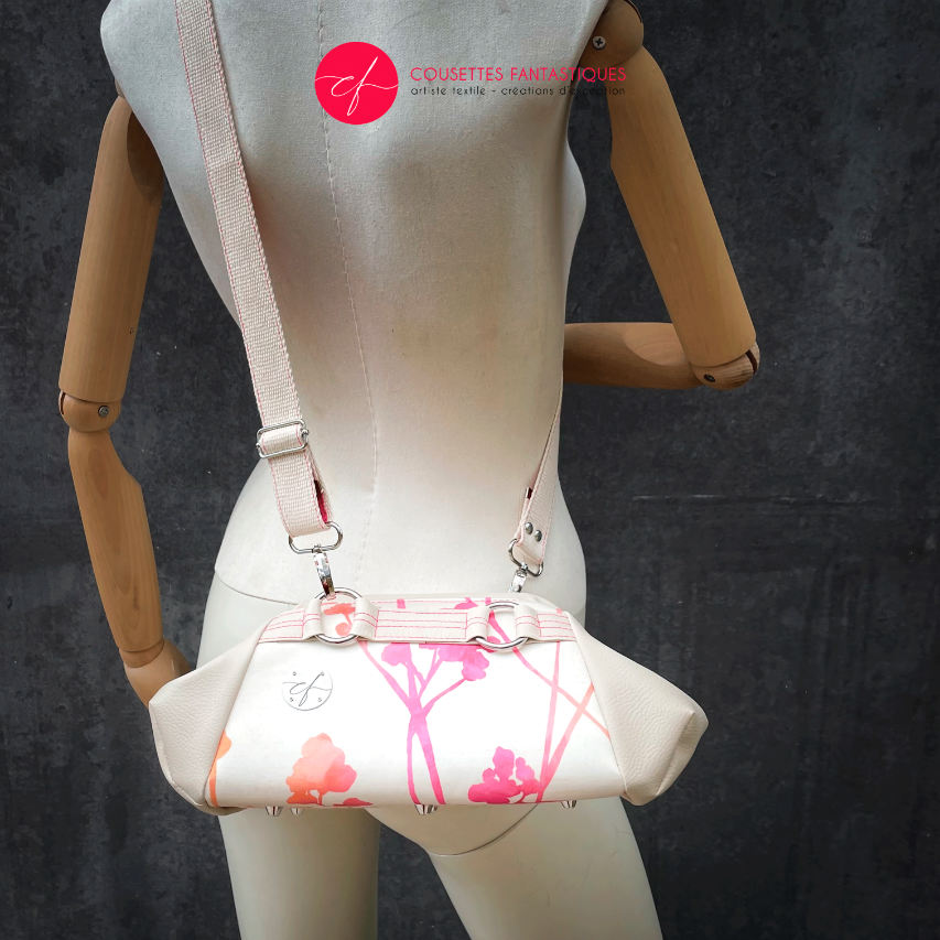 A small handbag made of cream synthetic upholstery fabric with a botanical pattern that fades from pink to orange.