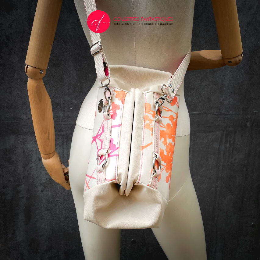 A small handbag made of cream synthetic upholstery fabric with a botanical pattern that fades from pink to orange.