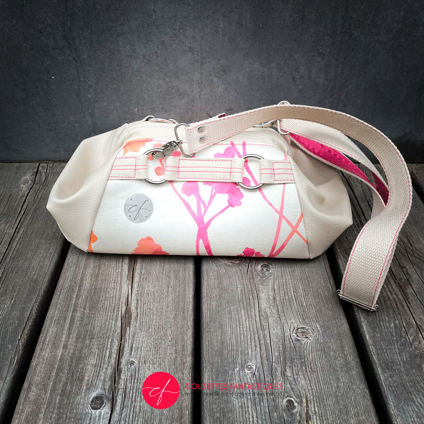 A small handbag made of cream synthetic upholstery fabric with a botanical pattern that fades from pink to orange.