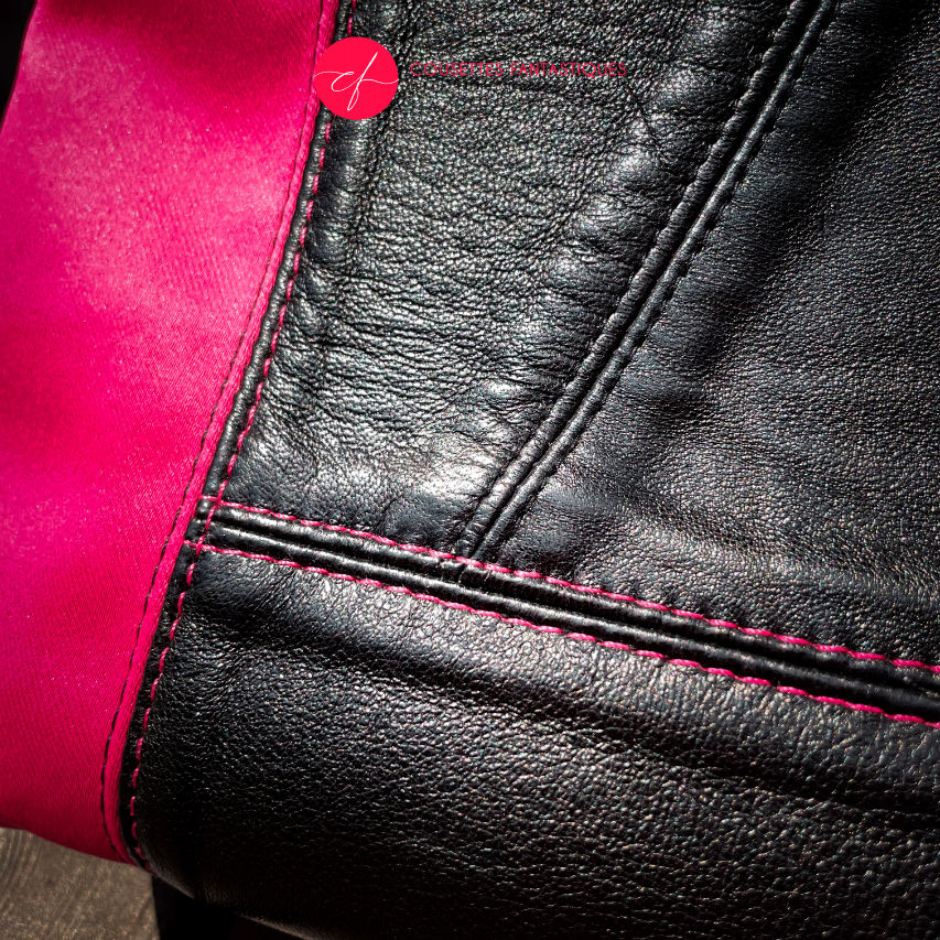 A backpack made with bright pink upholstery fabric, black leather, and wrap fabric with a floral pattern.