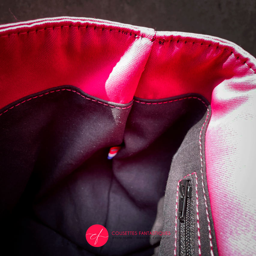 A backpack made with bright pink upholstery fabric, black leather, and wrap fabric with a floral pattern.