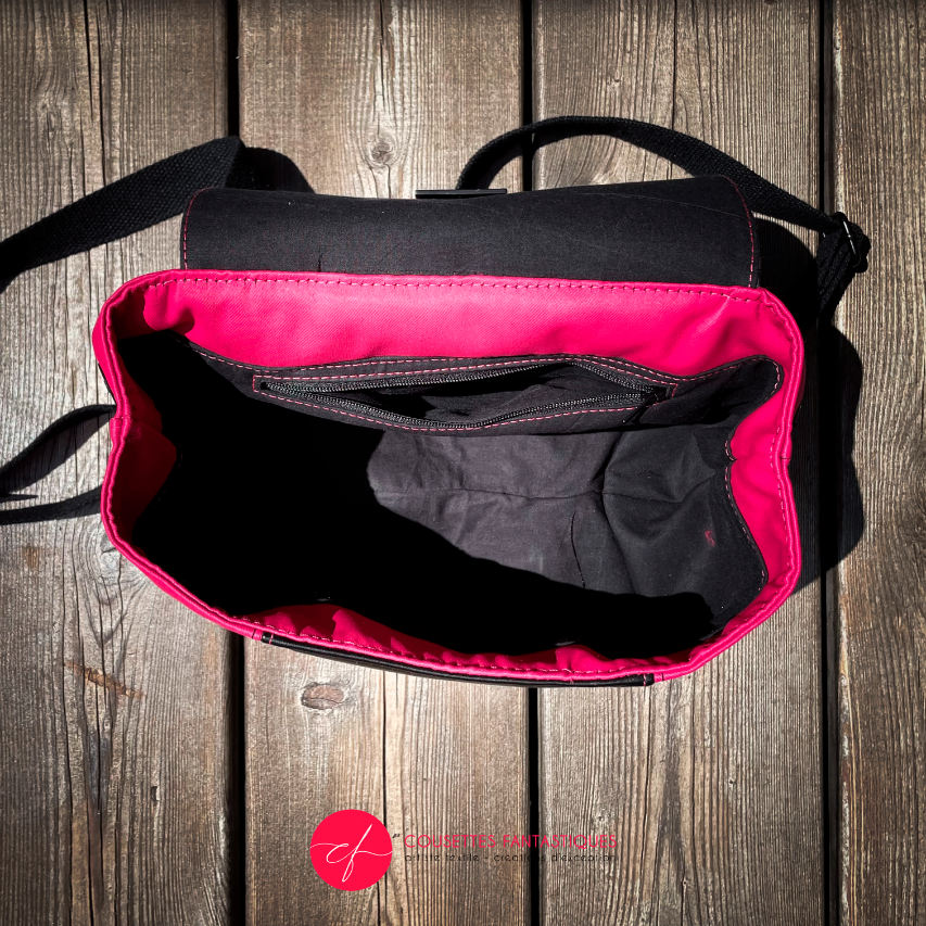 A backpack made with bright pink upholstery fabric, black leather, and wrap fabric with a floral pattern.