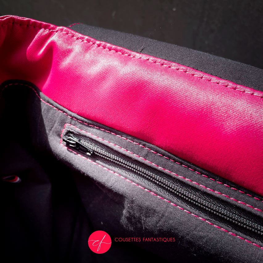 A backpack made with bright pink upholstery fabric, black leather, and wrap fabric with a floral pattern.