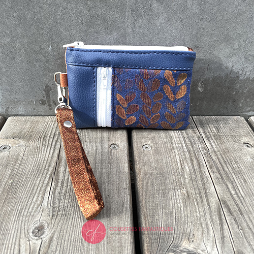A mini zippered coin purse made up of a patchwork of different materials: royal blue faux leather, golden faux leather, shiny bronze fabric, and blue and bronze wrap fabric with a pattern of small droplets.