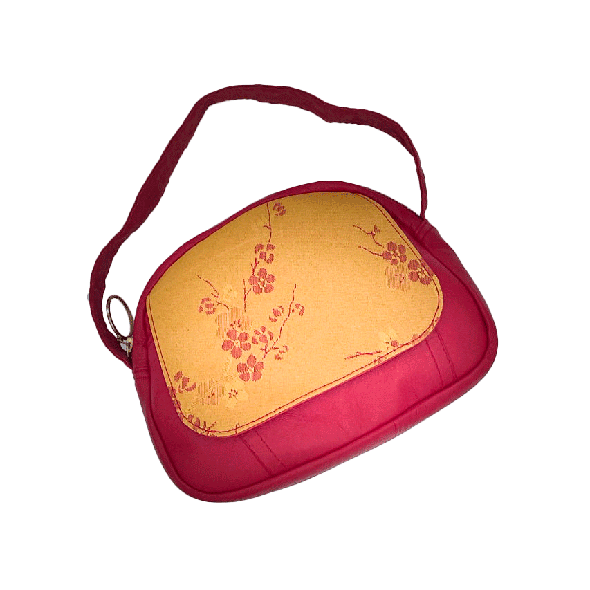 A mini handbag made of yellow upholstery fabric with a red cherry blossom pattern and red leather.