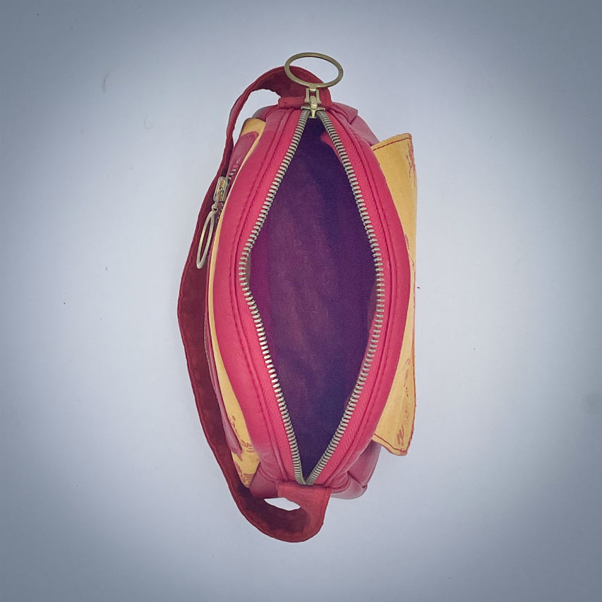 A mini handbag made of yellow upholstery fabric with a red cherry blossom pattern and red leather.