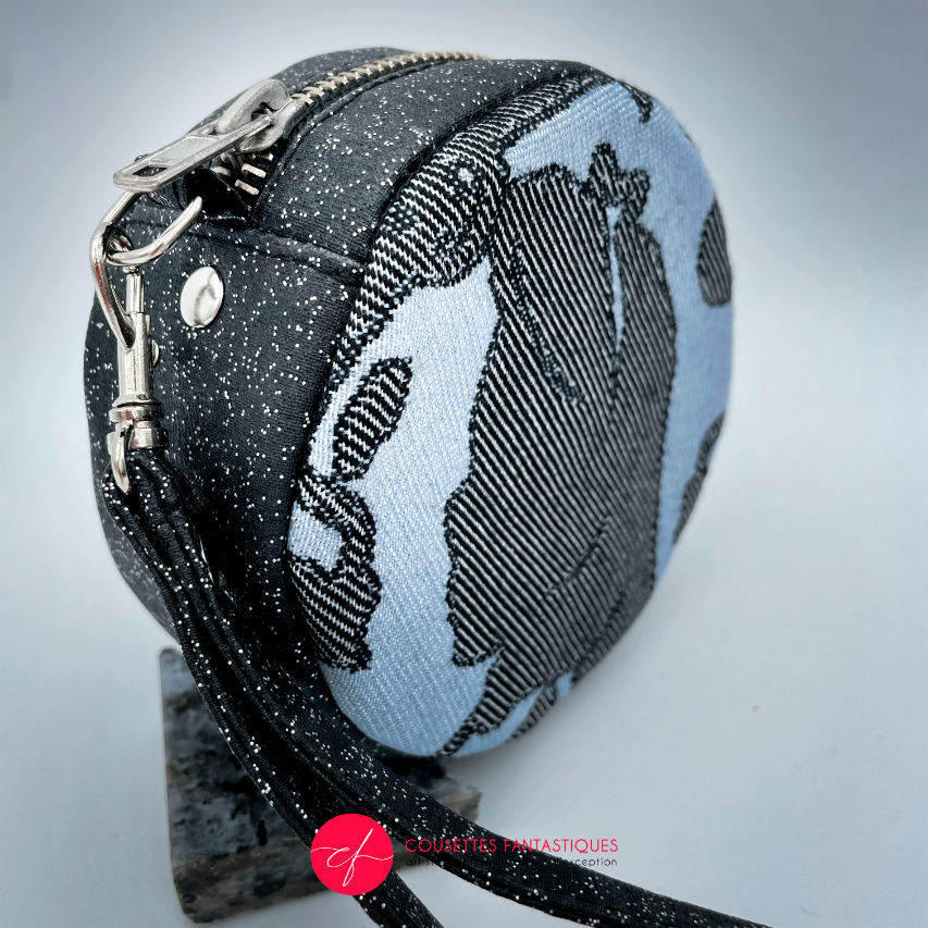 A round pouch made of multicolored glitter canvas and a gray-blue, black, and silver glitter babywearing wrap with a pattern inspired by the “Alice in Wonderland” story.
