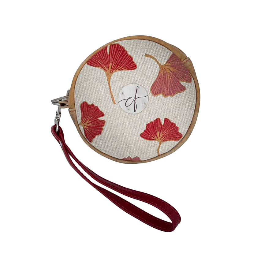A round pouch made of camel colored leather and a red Ginkgo Biloba leaves patterned polycotton canvas.