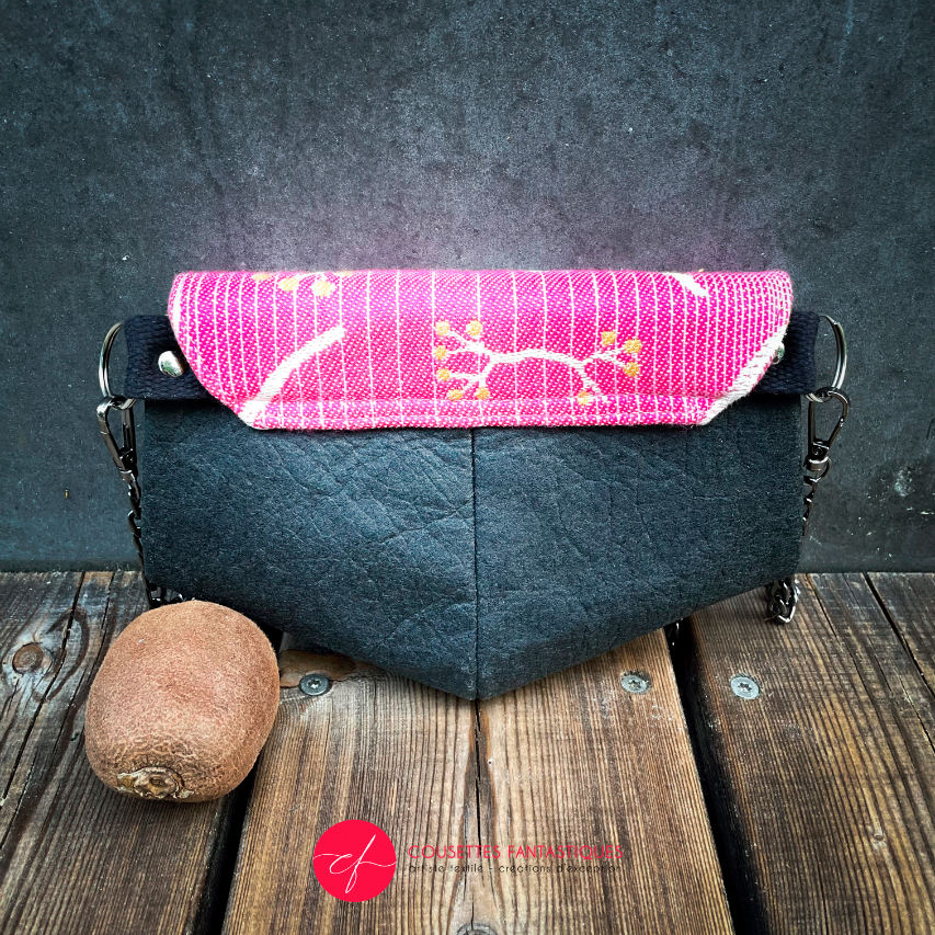 A small pouch made of pineapple-based faux leather in black and a pink, white, and yellow wrap fabric.