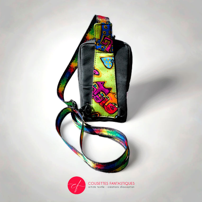 A small backpack made of matte black cork and a silk scarf with a colorful cat pattern, with a black and rainbow adjustable strap.