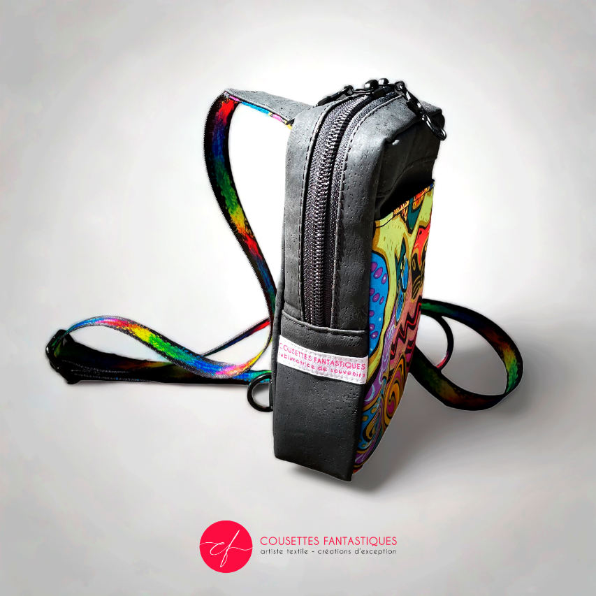 A small backpack made of matte black cork and a silk scarf with a colorful cat pattern, with a black and rainbow adjustable strap.