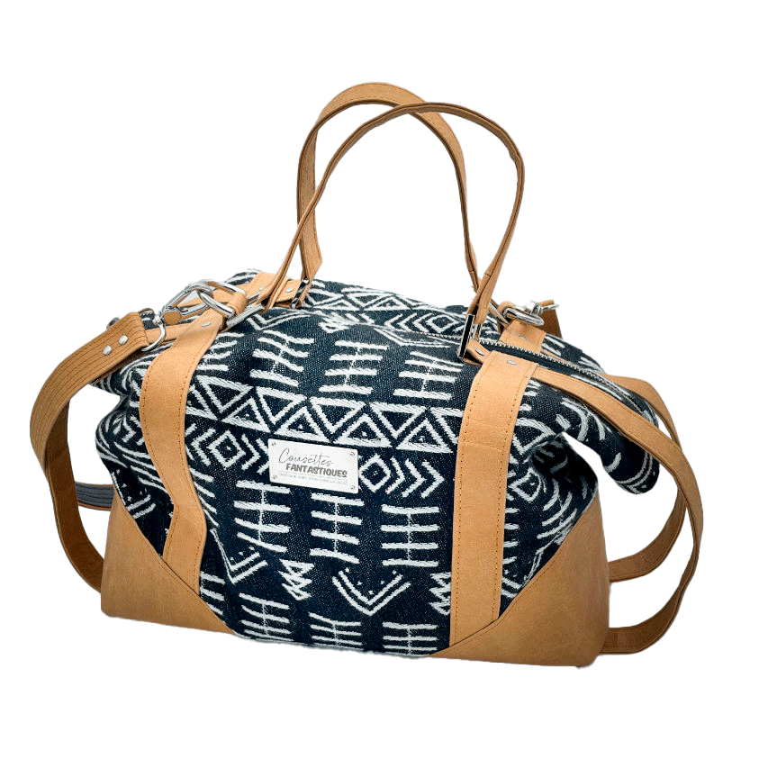 A small travel bag made of washable caramel paper, a black and white geometric patterned babywearing wrap, and grey poplin.