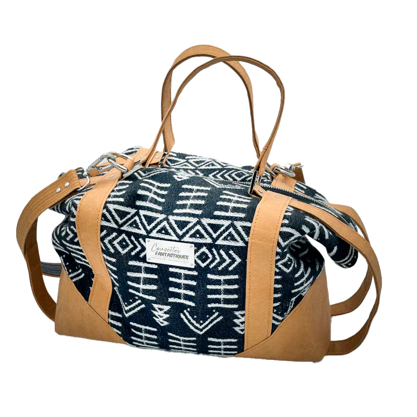 A small travel bag made of washable caramel paper, a black and white geometric patterned babywearing wrap, and grey poplin.