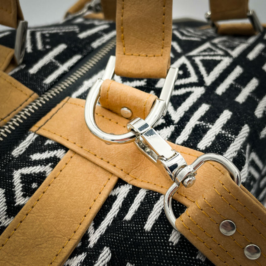 A small travel bag made of washable caramel paper, a black and white geometric patterned babywearing wrap, and grey poplin.