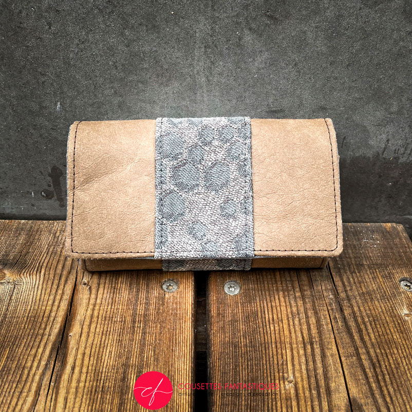 A wallet made of brown washable paper and a gray babywearing wrap with a hive pattern.