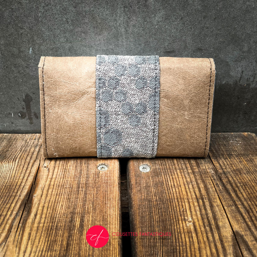 A wallet made of brown washable paper and a gray babywearing wrap with a hive pattern.