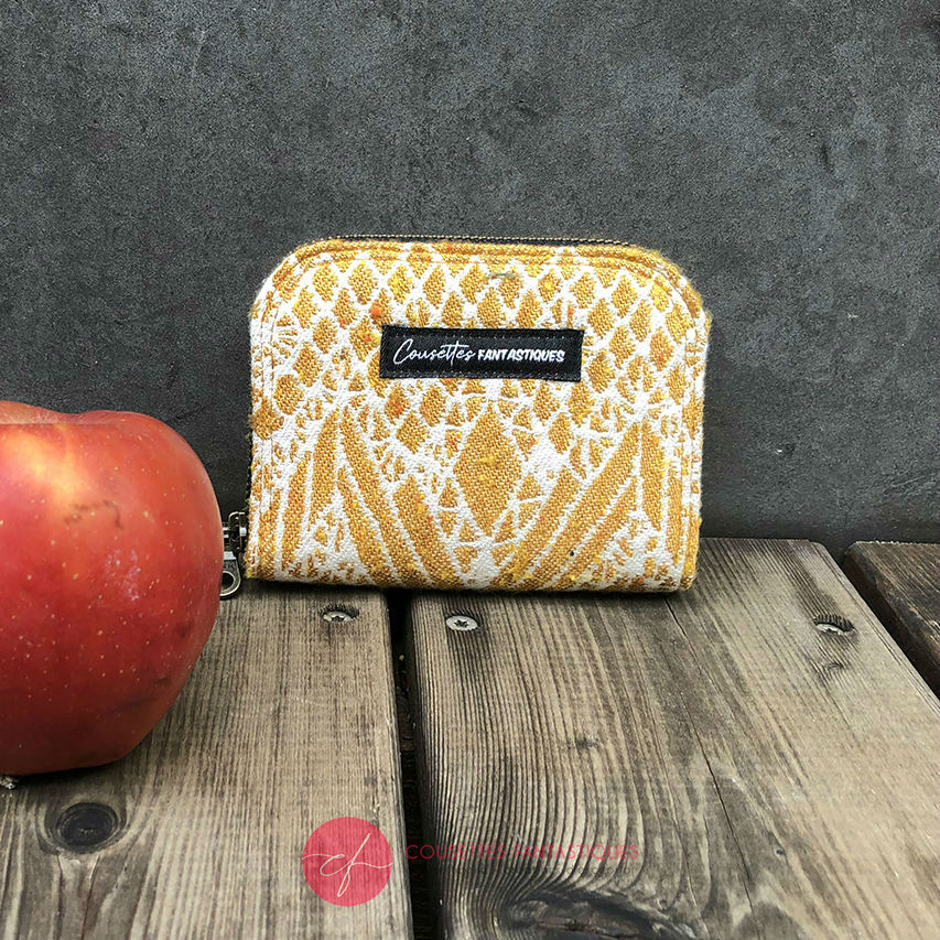 A small zippered card and coin holder made of gray fabric embroidered with blue, red, and white Scandinavian floral patterns.