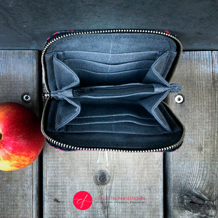 A small zippered card and coin holder made of gray fabric embroidered with shiny pink and red lines, with a textured gray matte interior.