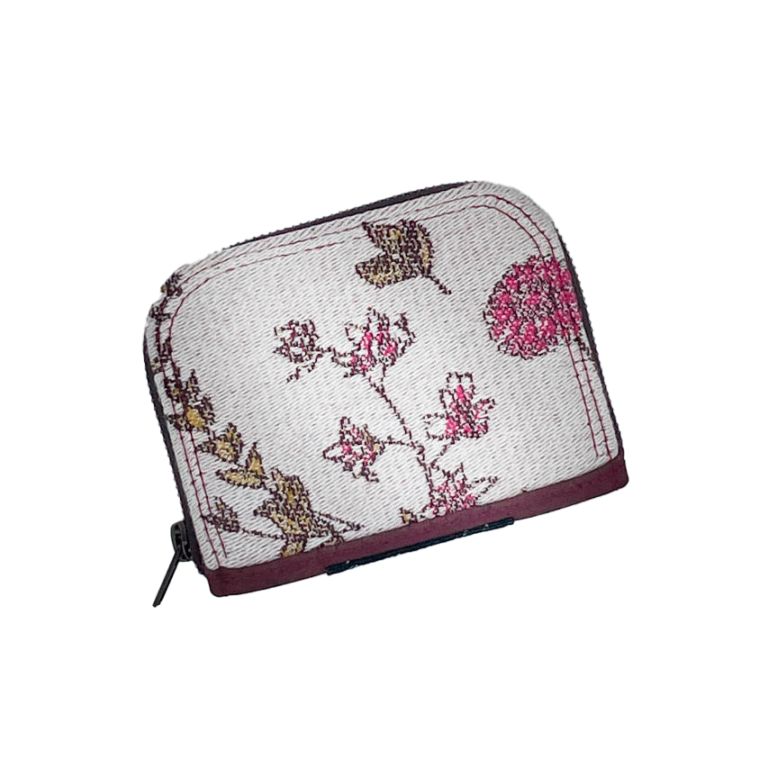 A small zippered card and coin holder made with fabric from a floral-patterned wrap in shades of pink on an ecru background and brick cork.