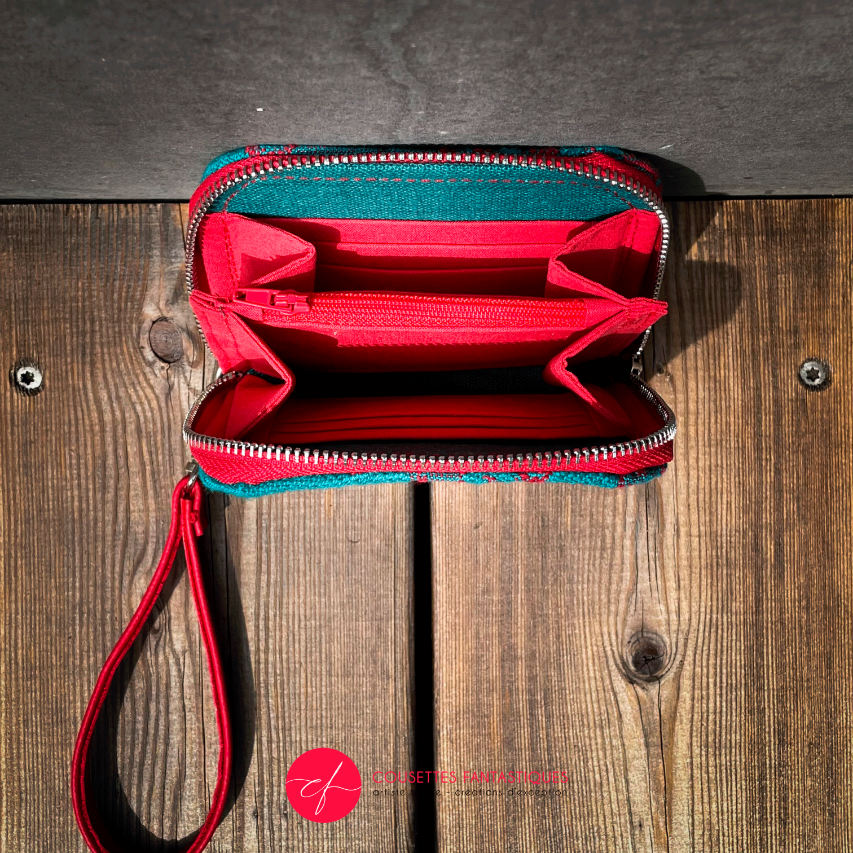 A small zippered card and coin holder made from blood-red and emerald green wrap fabric with thistle patterns and emerald green linen. It comes with a bright red faux leather wrist strap.