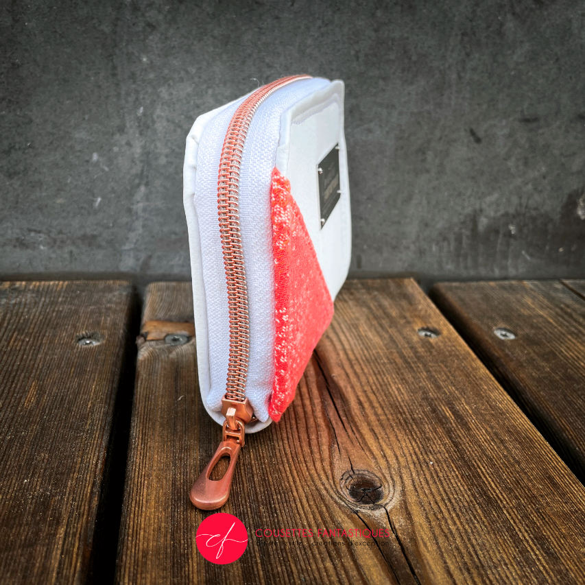 A small zippered card and coin holder made with gradient wrap fabric from orange-yellow to pink, with a pointillist star pattern, and white faux leather.