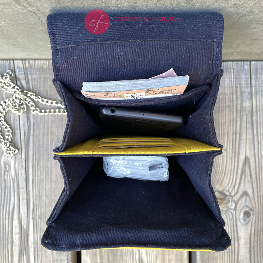 A phone-purse made from a gray, navy blue, and yellow babywearing scarf with bird motifs, and sun-yellow faux leather.