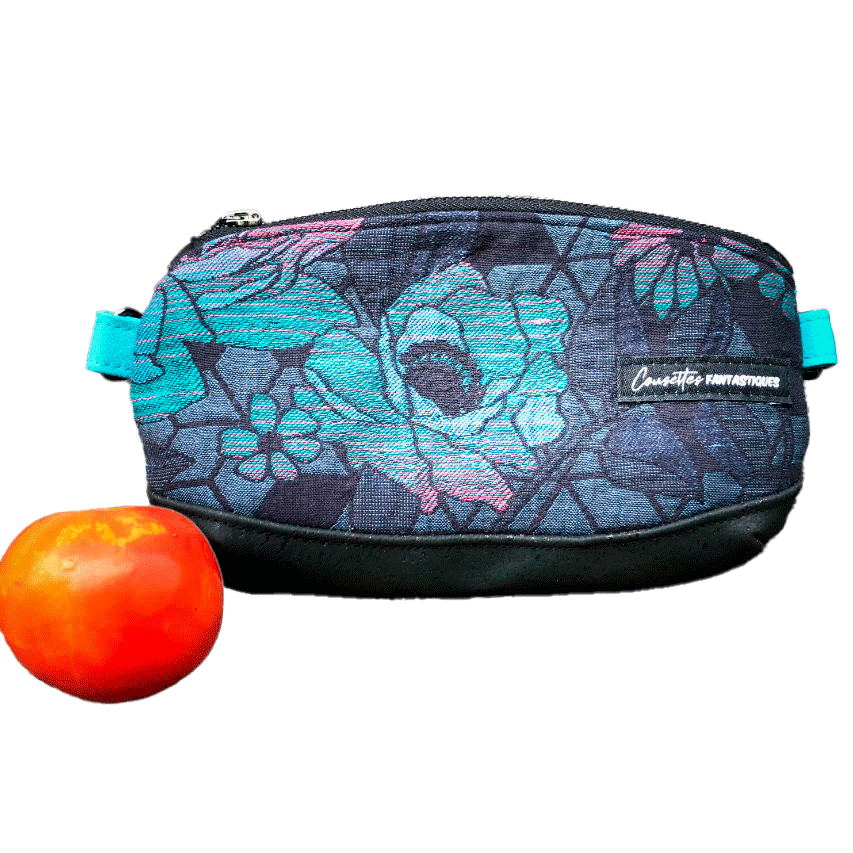 A small zippered clutch sewn in black cork and a babywearing wrap with geometric and floral patterns in shades of blue, green, and pink.