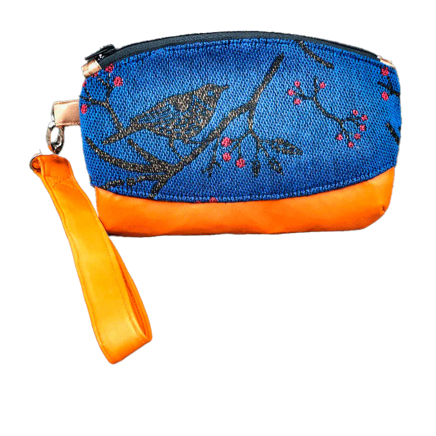 A small zippered clutch sewn in orange leather and a babywearing wrap in electric blue, black, and red with a motif of birds in branches.