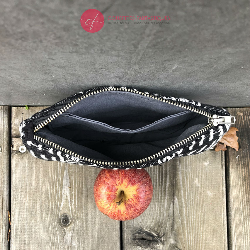 A small zippered clutch made of washable caramel paper, a black and white geometric patterned babywearing wrap, and grey poplin.