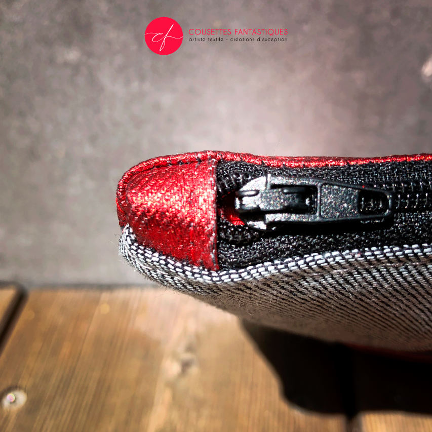 A zippered pouch sewn in gray reversible denim and metallic red, combined with bright red silk.