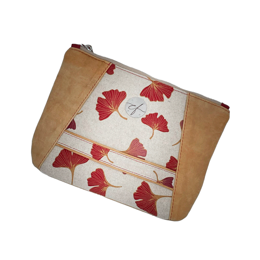 A zippered pouch sewn from a camel colored leather and a red Ginkgo Biloba leaves patterned polycotton canvas.