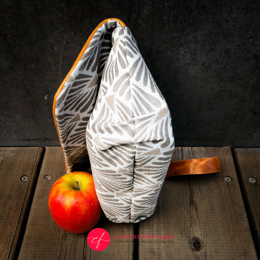 A flap clutch sewn in caramel leather, white damask, and vintage beige and gray patterned fabric, lined with taupe canvas.