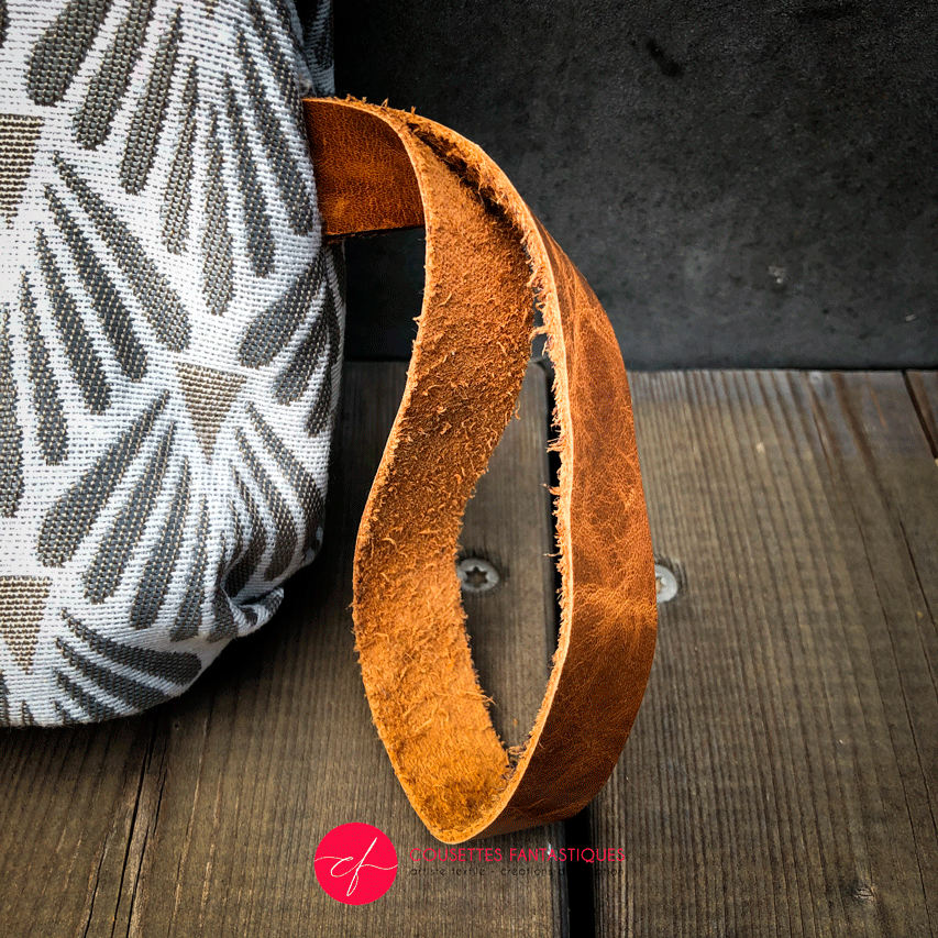 A flap clutch sewn in caramel leather, white damask, and vintage beige and gray patterned fabric, lined with taupe canvas.