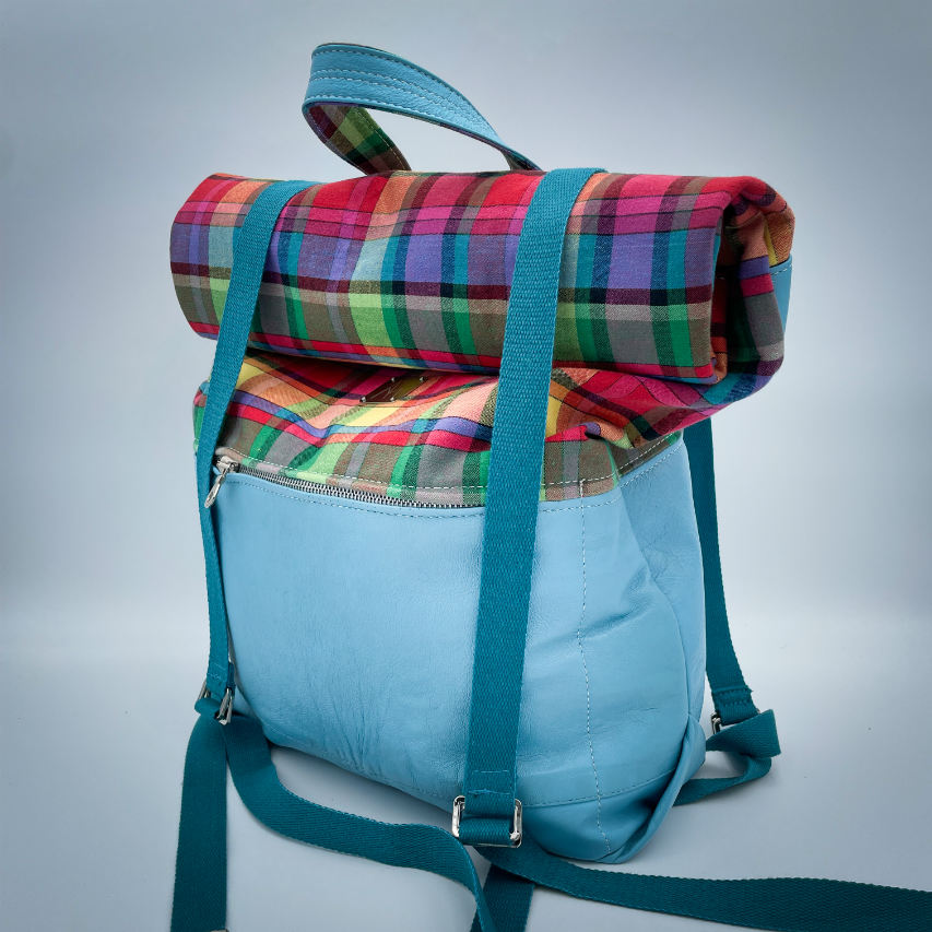 A rucksack made of light turquoise blue leather and multicolored Madras fabric.