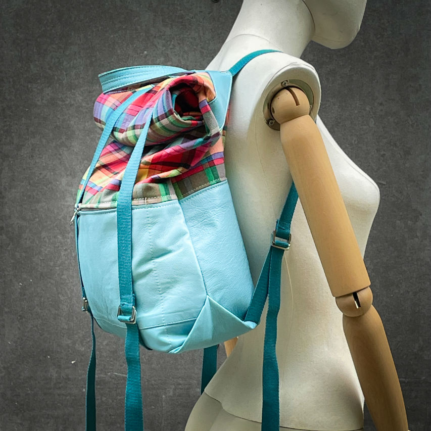 A rucksack made of light turquoise blue leather and multicolored Madras fabric.