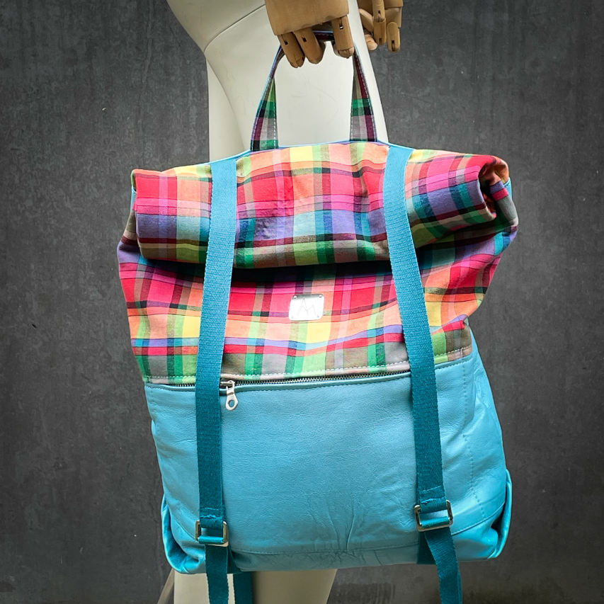 A rucksack made of light turquoise blue leather and multicolored Madras fabric.