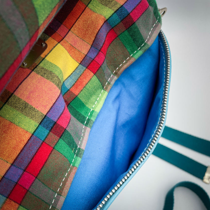 A rucksack made of light turquoise blue leather and multicolored Madras fabric.