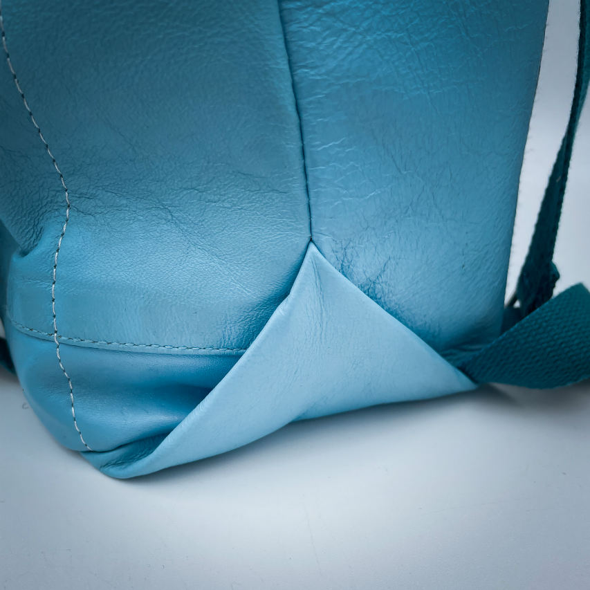 A rucksack made of light turquoise blue leather and multicolored Madras fabric.