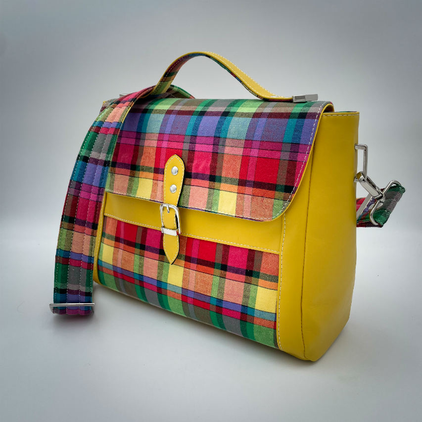 A satchel made of blood-red faux leather and multicolored madras fabric.